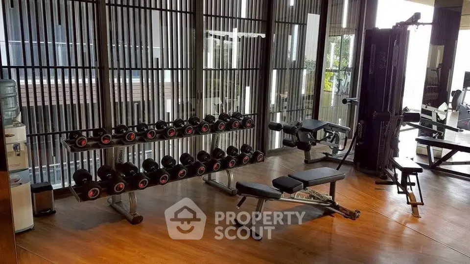 Modern gym with state-of-the-art equipment and floor-to-ceiling windows in luxury building.