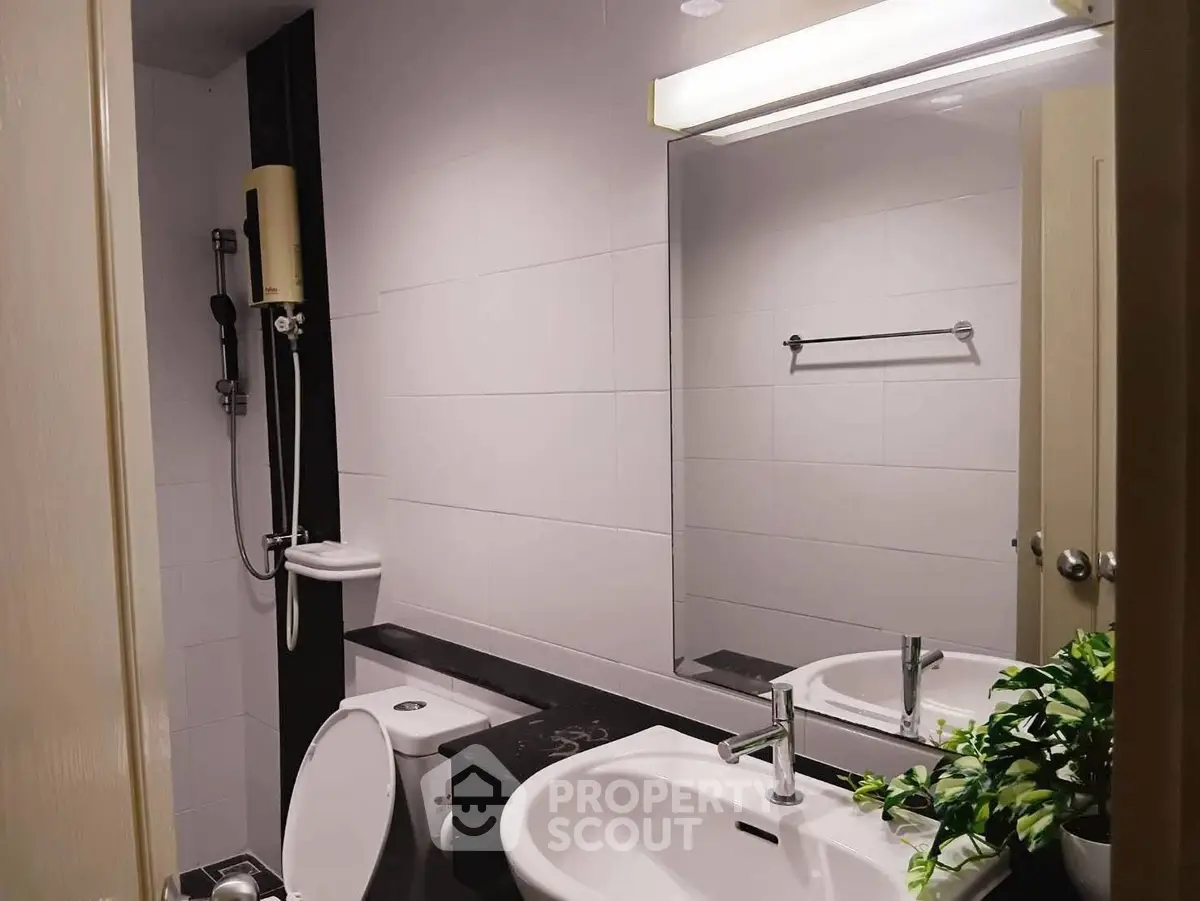 Modern bathroom with sleek fixtures and large mirror, featuring a shower and elegant sink design.