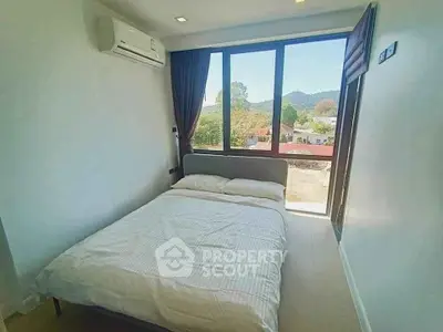 Bright bedroom with large window and scenic view of mountains.