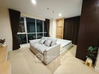 Modern bedroom with city view, featuring a stylish sofa and elegant decor.