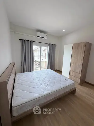 Spacious bedroom with modern wooden furniture and large window for natural light.