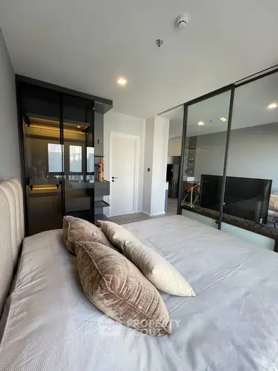 Modern bedroom with sleek design and glass partition, featuring plush bedding and stylish decor.
