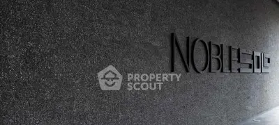 Elegant building entrance with modern design and textured wall showcasing luxury real estate.