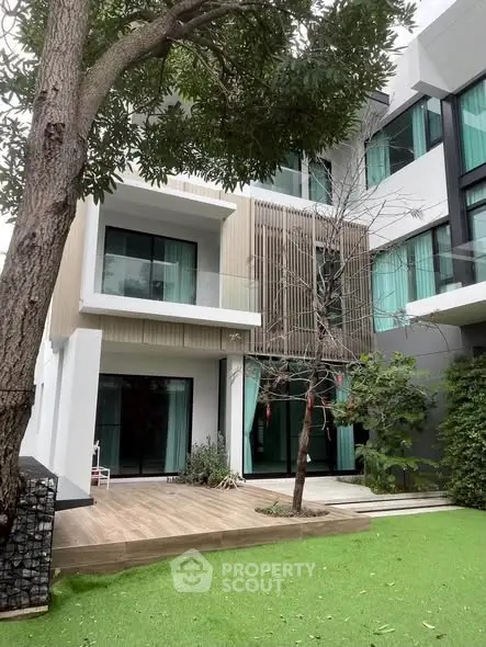 Modern multi-story house with large windows and lush green garden