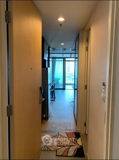 Modern apartment hallway leading to a bright living area with large windows and stylish decor.