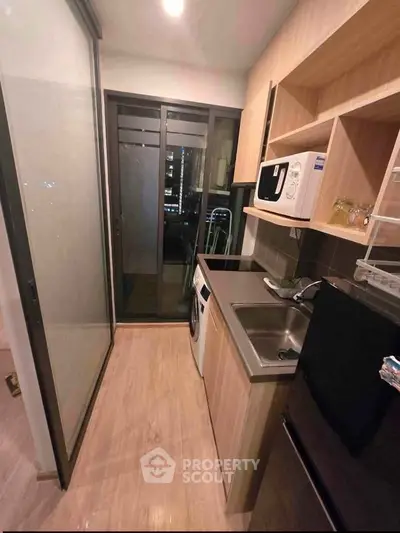 Modern compact kitchen with sleek appliances and city view, perfect for urban living.