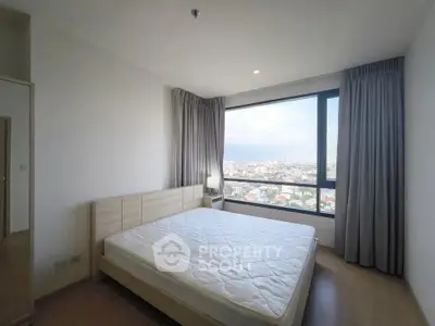 Spacious bedroom with large window offering stunning city views