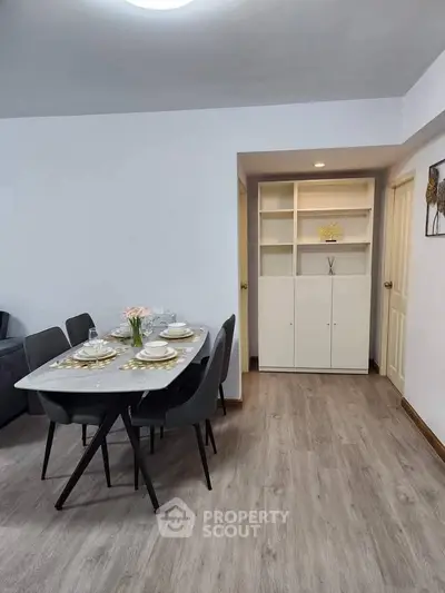 Modern dining area with elegant table setting and built-in shelving in a cozy apartment.