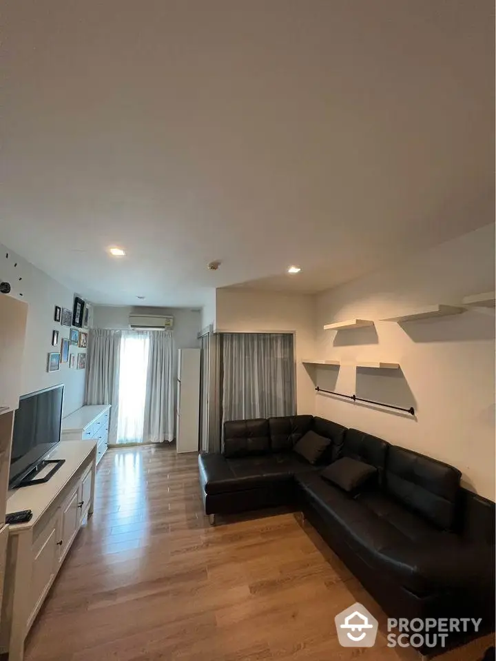 Spacious living room with elegant hardwood flooring, large comfortable sectional sofa, and modern lighting, perfect for entertaining and relaxation.