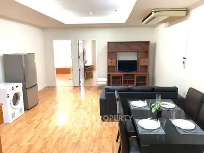 Spacious living room with dining area, modern furniture, and hardwood floors in a stylish apartment.