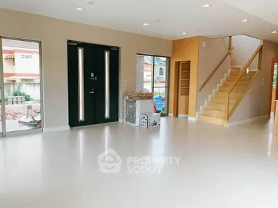 Spacious modern living room with sleek staircase and large windows.