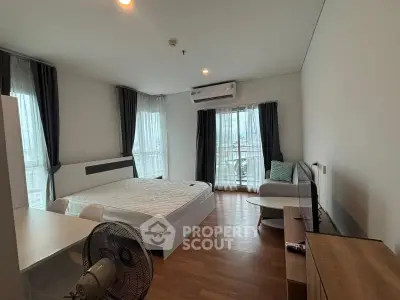 Spacious bedroom with modern furnishings and large windows offering city views.