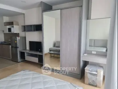 Modern studio apartment with sleek wardrobe and compact kitchen area, ideal for urban living.