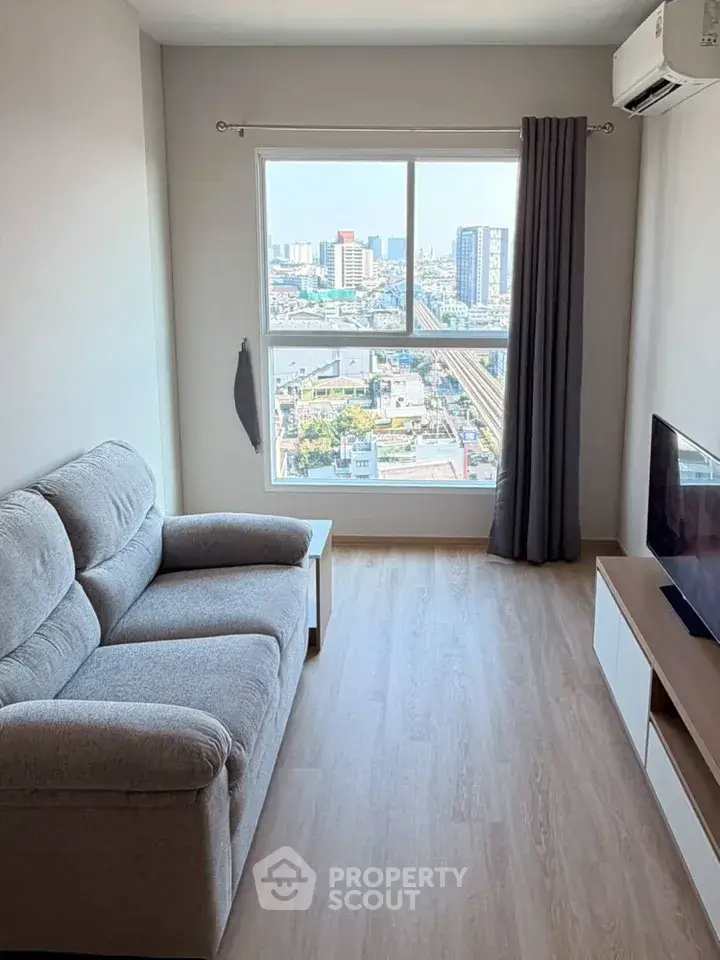 Modern living room with city view, featuring cozy sofa and sleek TV setup, perfect for urban living.