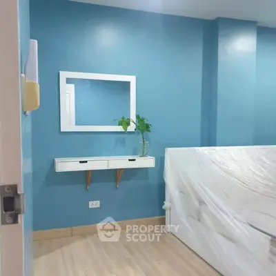Modern bedroom with blue walls, minimalist decor, and a sleek wall-mounted shelf.