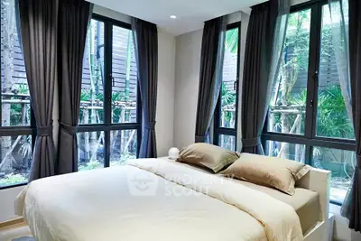 Spacious bedroom with large windows and garden view, featuring elegant curtains and cozy bedding.
