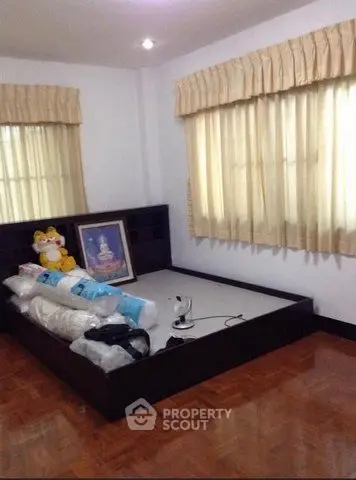 Spacious bedroom with wooden flooring and large windows for natural light.