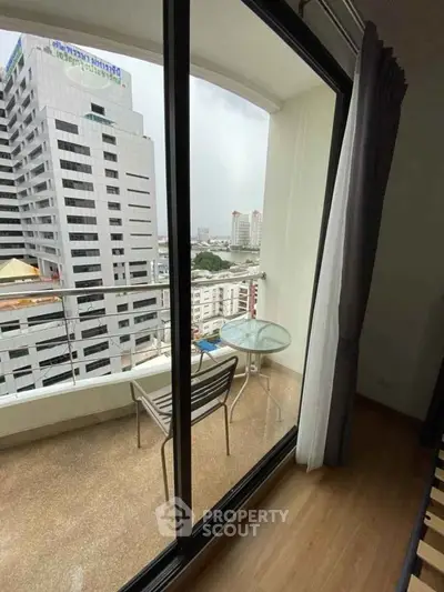 Modern apartment balcony with city view and glass table set