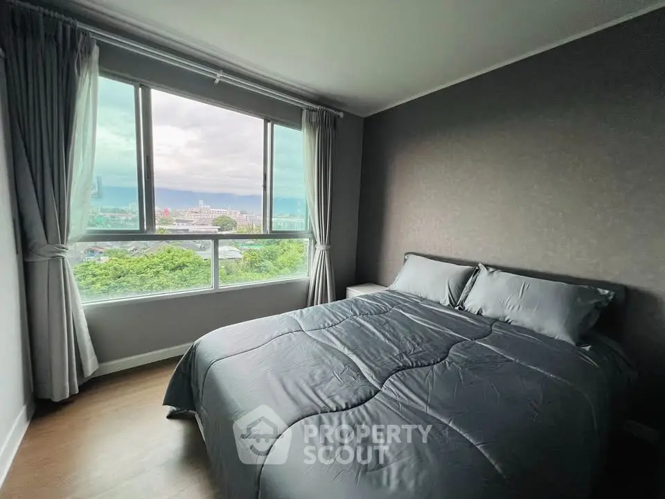 Cozy bedroom with large window offering stunning cityscape views