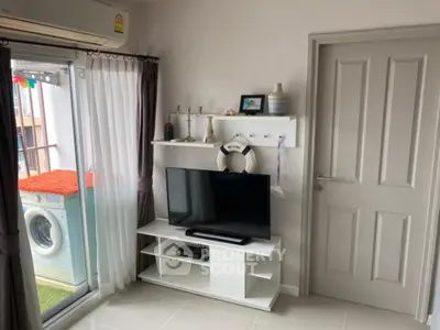 Cozy living room with TV and balcony view featuring washing machine.