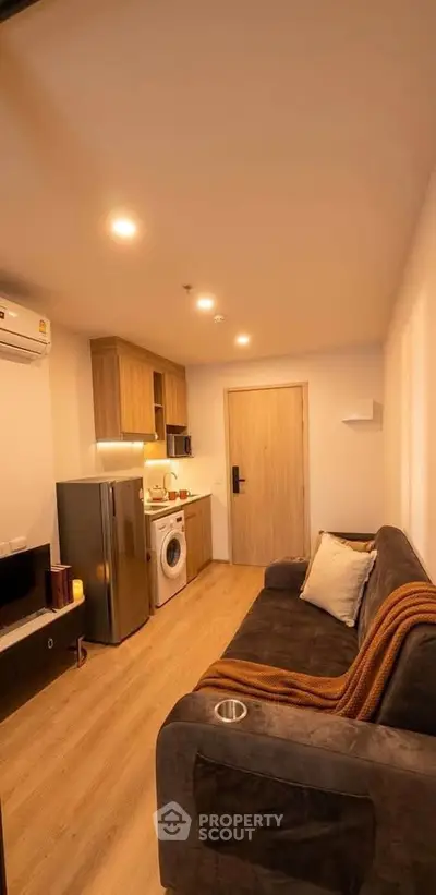 Cozy living room with modern appliances and stylish decor in a compact apartment.