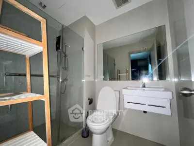 Modern bathroom with glass shower and sleek fixtures in contemporary apartment.