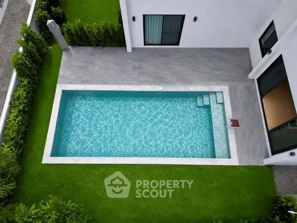 Modern home with private pool and lush green lawn, perfect for luxury living.