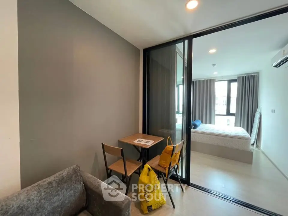 Modern apartment interior with cozy living area and glass partitioned bedroom