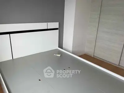 Modern bedroom with sleek bed frame and built-in wardrobe, showcasing minimalist design.
