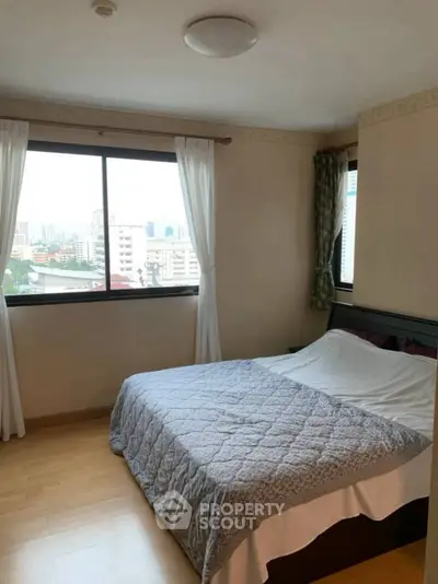 Cozy bedroom with large window offering city views and natural light.