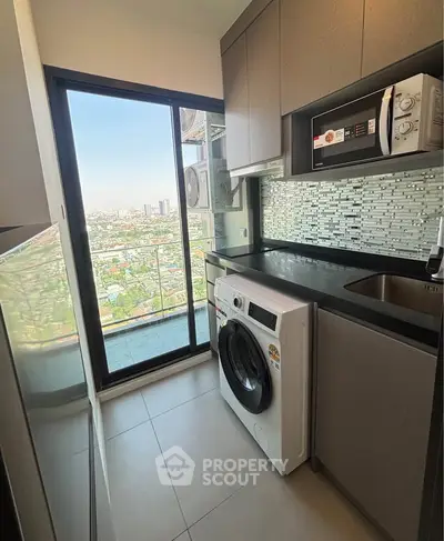 Modern kitchen with washing machine and stunning city view from balcony.