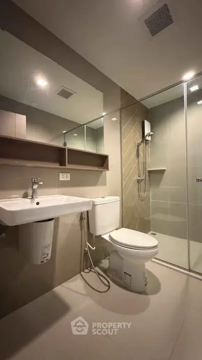 Modern bathroom with sleek fixtures and glass shower enclosure in a contemporary apartment.