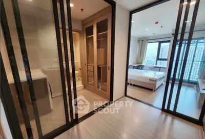 Modern apartment interior with glass doors, showcasing a bedroom and bathroom with city view.