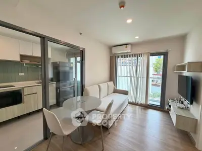 Modern living room with open kitchen, featuring sleek furniture and natural light.
