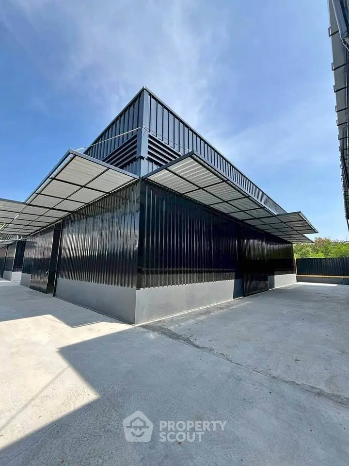 Modern industrial-style building with sleek black metal exterior and spacious outdoor area.