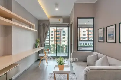 Modern living room with sleek design, large window, and cozy seating area in a stylish apartment.