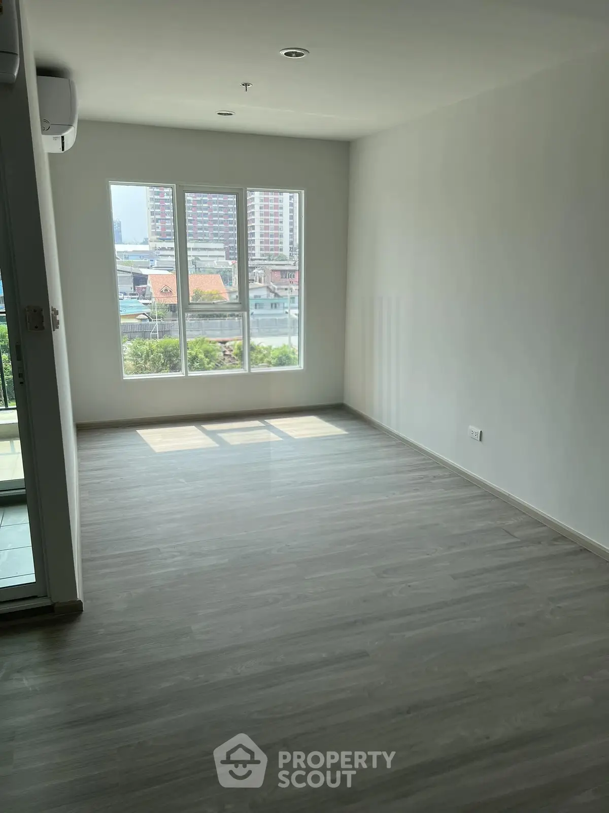 Spacious empty room with large windows offering city view and natural light, perfect for customization.