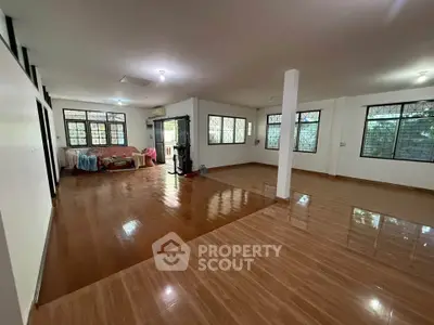 Spacious open-plan living area with wooden flooring and large windows