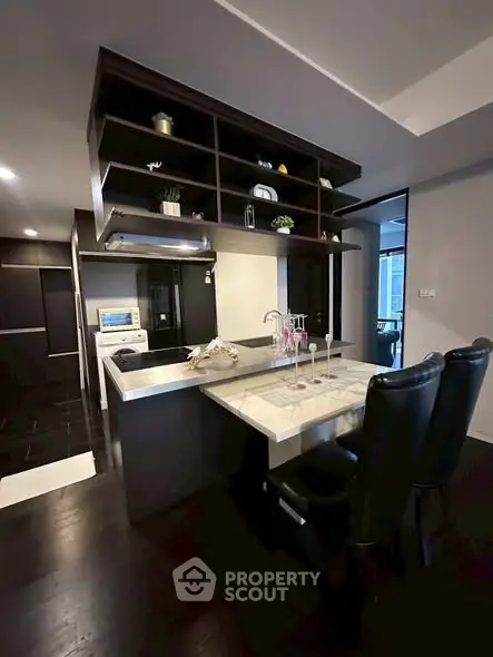 Modern kitchen with sleek design and open layout, featuring dark cabinetry and stylish countertops.