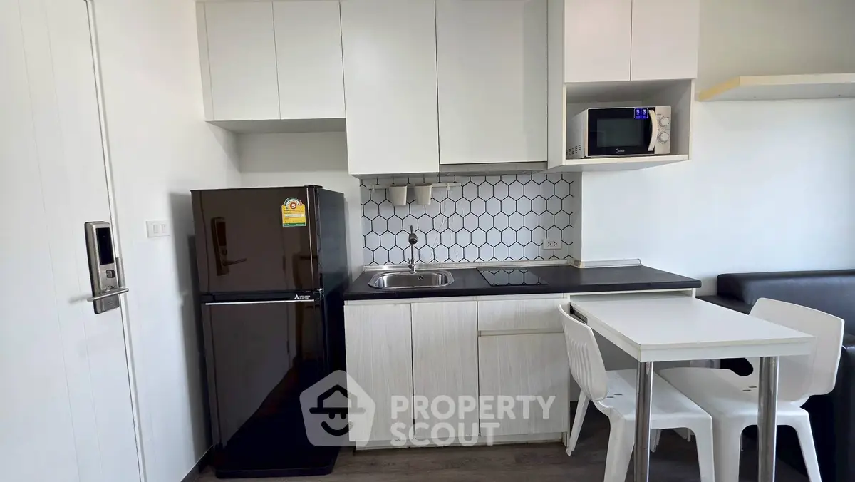 Modern compact kitchen with sleek black fridge and white cabinetry