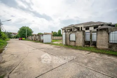 Spacious suburban street view with gated residential property and lush greenery.