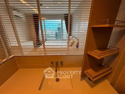 Modern bathroom with sleek sink and city view through blinds, showcasing luxury urban living.