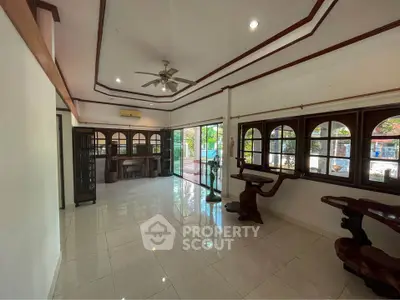 Spacious living room with polished tile flooring, traditional wood trim, and ample natural light from large windows, perfect for family gatherings.