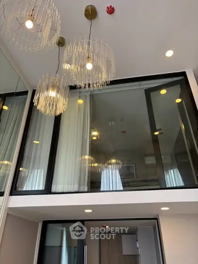 Modern duplex apartment with elegant lighting and glass balcony, showcasing contemporary design and high ceilings.