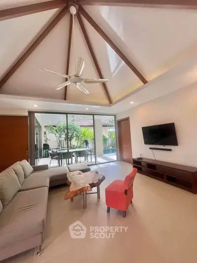 Spacious living room with modern decor and garden view, featuring a cozy sofa and stylish ceiling fan.