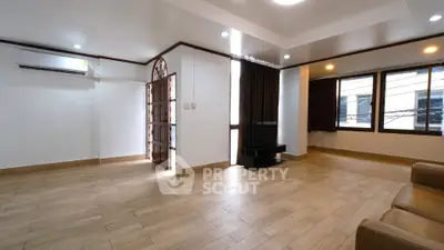 Spacious living room with wooden flooring and modern lighting in a stylish apartment.