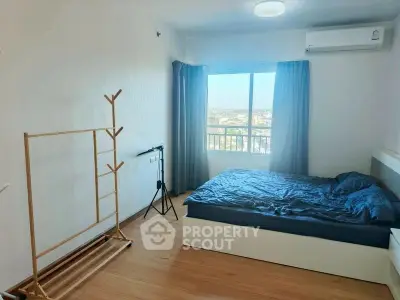 Bright bedroom with wooden flooring and large window offering scenic views.