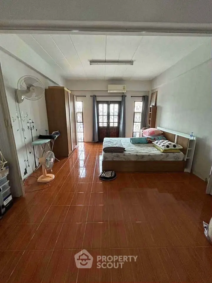 Spacious bedroom with natural light and tiled flooring, featuring a cozy bed and ample storage space.