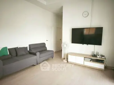 Spacious modern living room with sleek furniture and wall-mounted TV, perfect for relaxation and entertainment.
