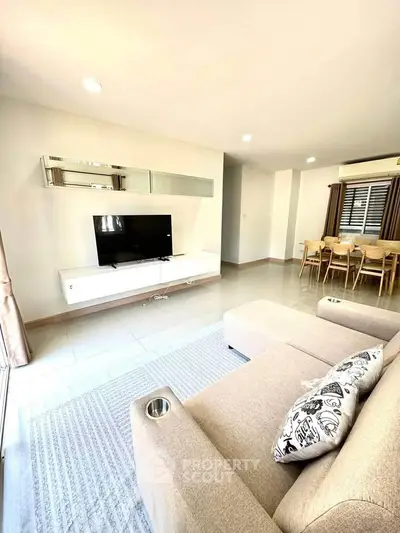 Spacious living room with modern decor and large TV, perfect for relaxation and entertainment.